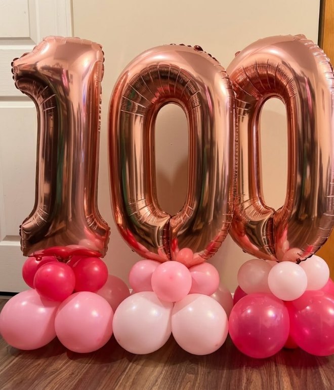 Rose gold 100 number balloons on pink and white balloon bases